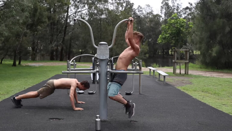 Two guys exercising on machines outside in the park